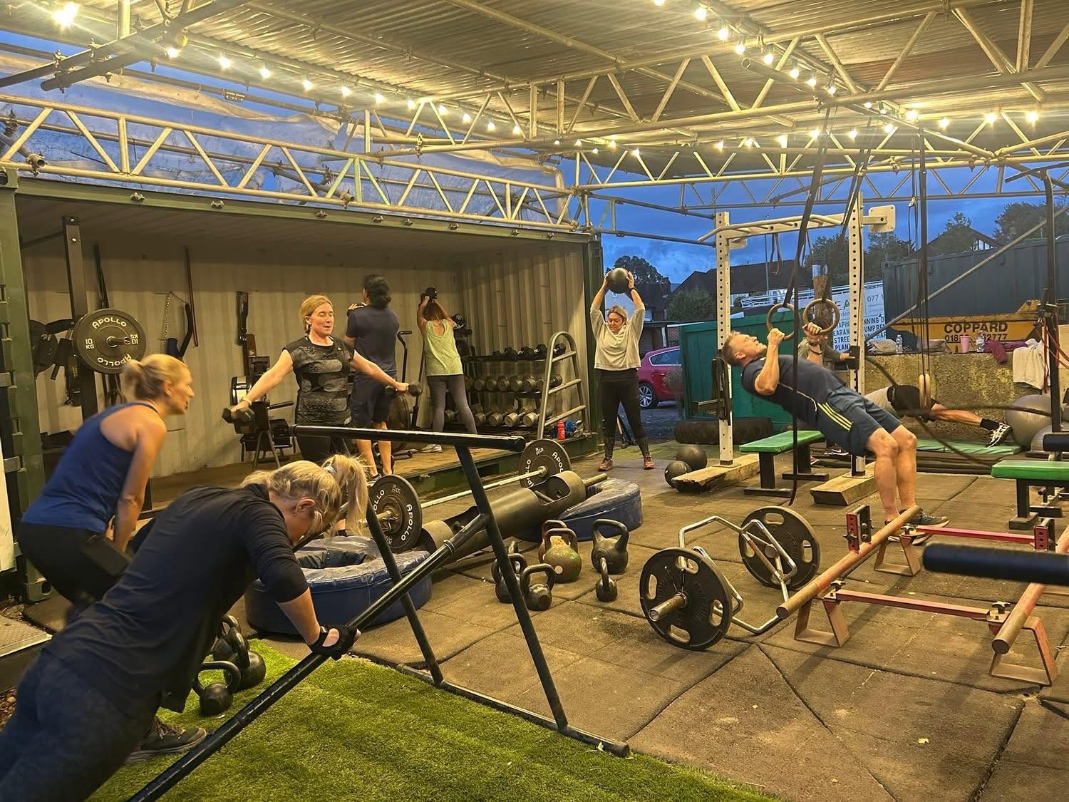 a group of both men and women exercising outside, doing circuit training